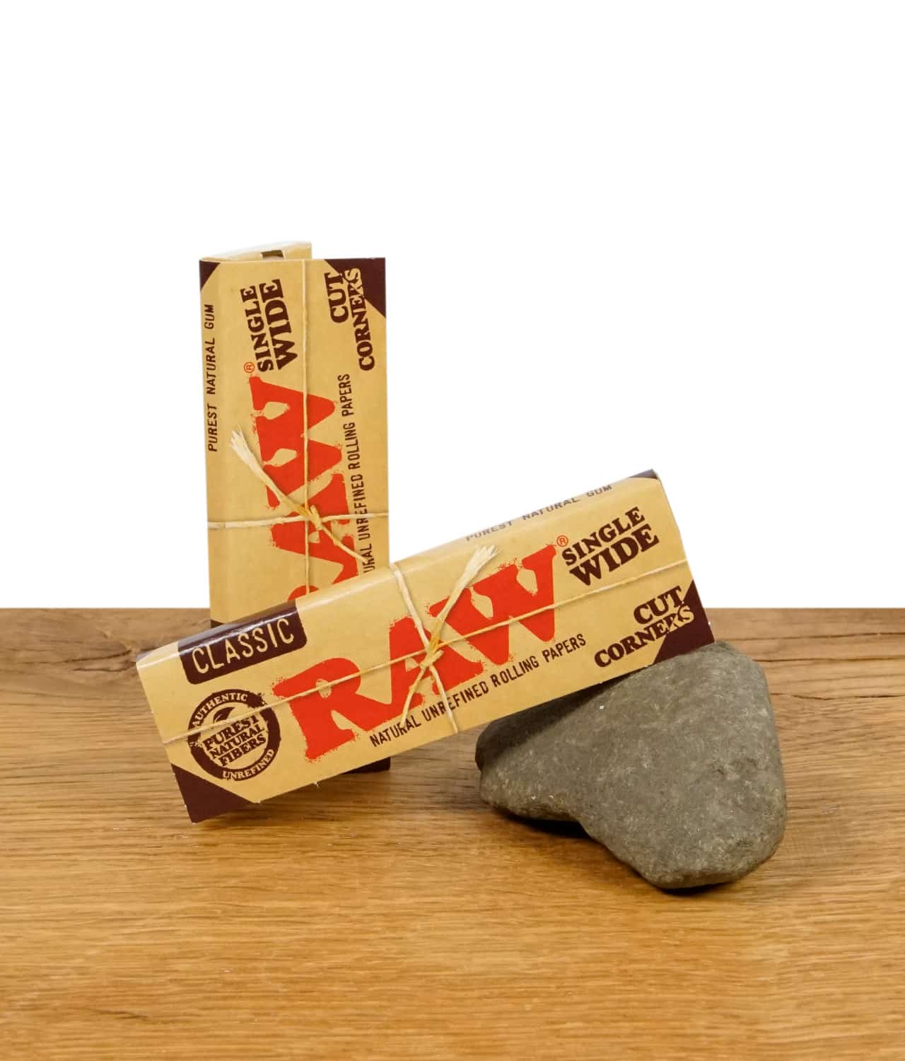 raw-single-wide-cut-corners-1-jpg Zwei Packungen RAW Classic Rolling Papers im Single Wide Format mit Cut Corners, auf einem Stein präsentiert