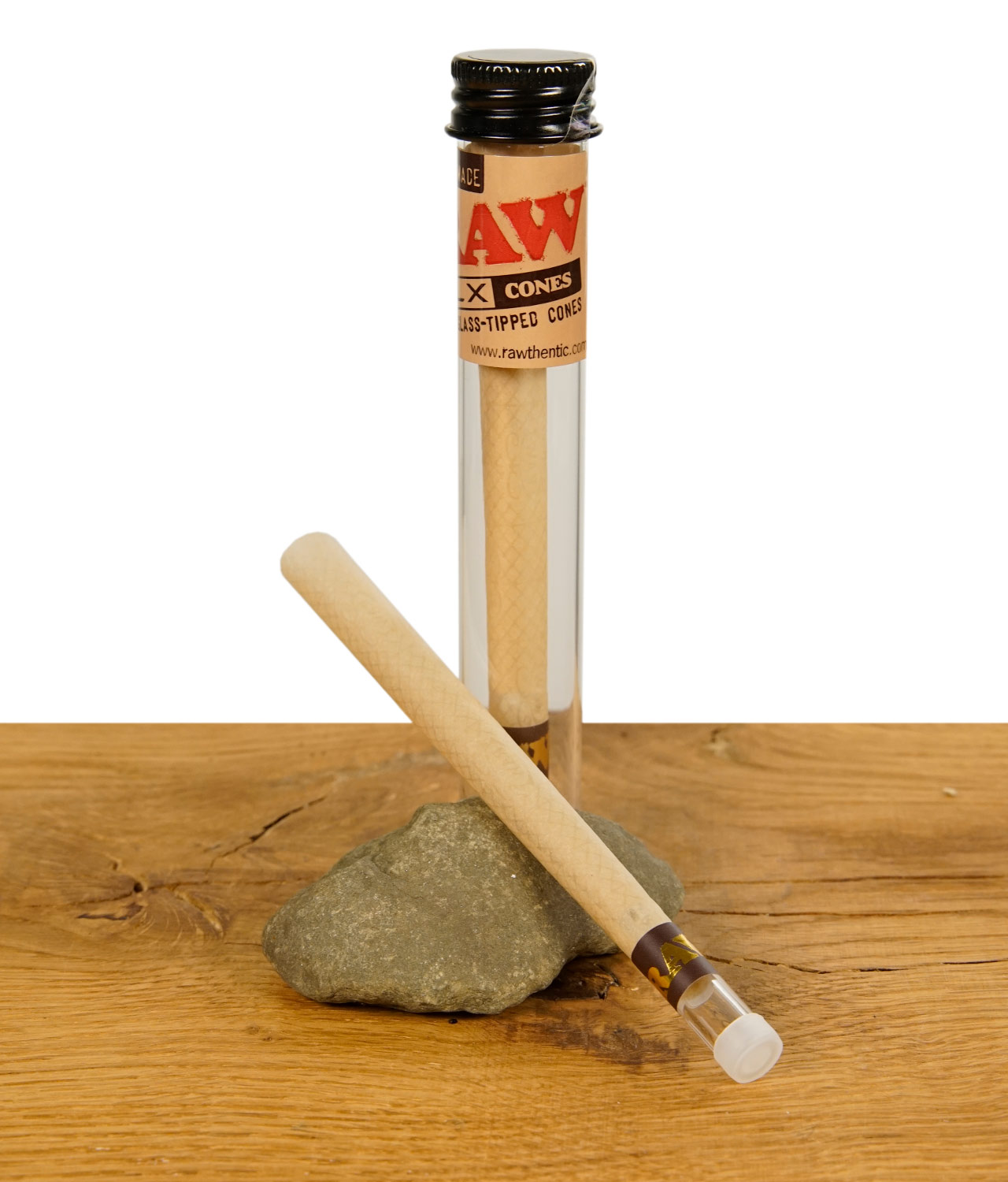dlx-glass-tipped-cone-cones-jpg Zwei RAW DLX Glass Tipped Cones, einer im Glasröhrchen und einer daneben auf einem Stein liegend, auf einem Holzuntergrund.