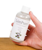 Hand hält eine Flasche LimPuro Bio Cleaner Konzentrat mit sichtbarer Schaumbildung im oberen Bereich.