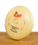 RAW Frisbee-Scheibe in Beige mit Branding, stehend auf einer Holzoberfläche.