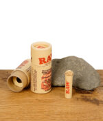 RAW Rose Tip – vorgerollter Filter mit kunstvoller Rosenspitze in umweltfreundlicher Kartonverpackung auf Holztisch mit Stein.