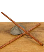 Zwei RAW Wooden Pokers – lange Holztamper für Cones, gekreuzt auf einem Stein liegend, präsentiert auf Holztisch.