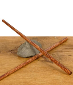 Zwei RAW Wooden Pokers – lange Holztamper für Cones, gekreuzt auf einem Stein liegend, präsentiert auf Holztisch.