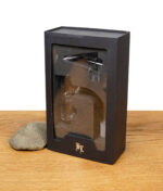 Verpackter Glasbanger in einer eleganten schwarzen Box mit Sichtfenster und BL-Logo auf einem Holztisch mit Stein.