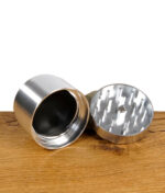 Zerlegter True Fruits Grinder aus Aluminium auf Holztisch.