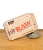 RAW Starter Box Classic mit Metalldose auf einem Stein stehend, auf Holzoberfläche platziert