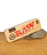 RAW Metal Tin Case King Size geschlossen auf einem Stein platziert auf Holztisch