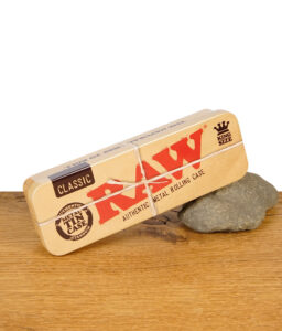 RAW Metal Tin Case King Size geschlossen auf einem Stein platziert auf Holztisch