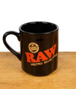 Schwarze RAW Tasse mit rotem RAW Logo und unrefined rolling papers Schriftzug auf Holztisch