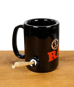 RAW Tasse mit Chillumfunktion befüllt mit Joint aufgestellt auf Holzfläche