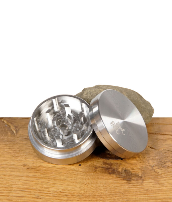 Geöffneter Black Leaf Edelstahlgrinder, 2-teilig mit 39 mm Durchmesser, liegend auf Holztisch – Schleifzähne und Deckel sichtbar
