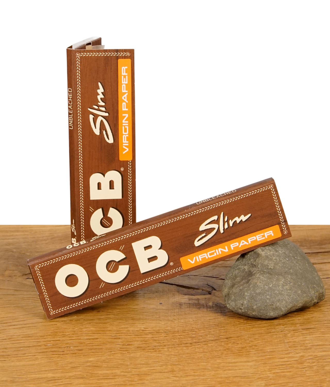 ocb-slim-virgin-papers-unbleached-jpg Zwei geschlossene Packungen OCB Virgin Paper King Size Slim ungebleicht auf Holztisch mit Stein als Stütze