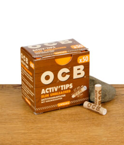 OCB Activ'Tips Slim Aktivkohlefilter ungebleicht im 50er Pack – geschlossene Packung mit zwei losen Filtern auf Holztisch