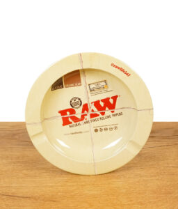 RAW Aschenbecher aus Metall mit typischem RAW Classic Design, stehend auf einem Holztisch