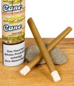 Zwei vorgerollte Cyclones Hemp Cones Cane mit Holzfilter neben der Verpackung auf Holztisch