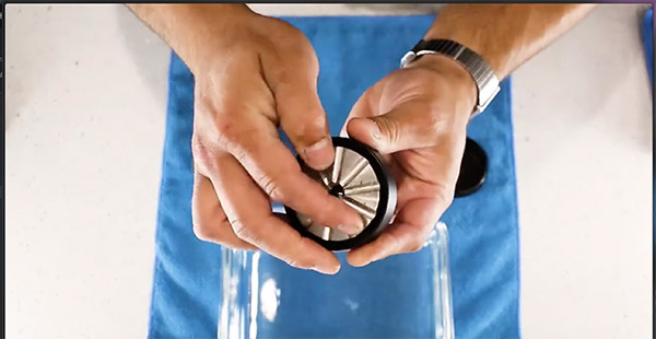 Reinigung eines Flower Mill Grinders über einer Glasschale.