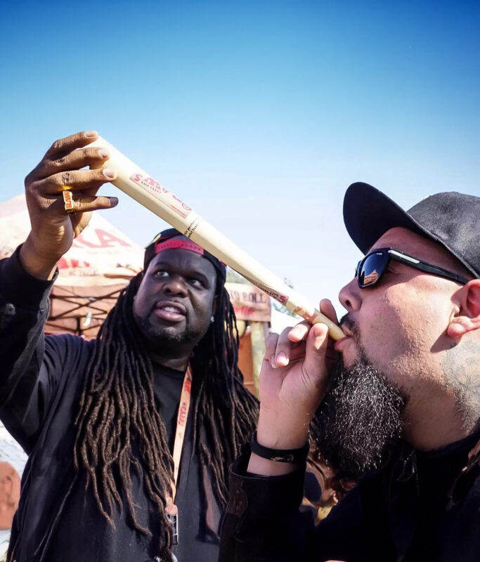 Zwei Personen mit einem übergroßen RAW Cones Joint bei einem Outdoor-Event, im Hintergrund RAW-Branding.