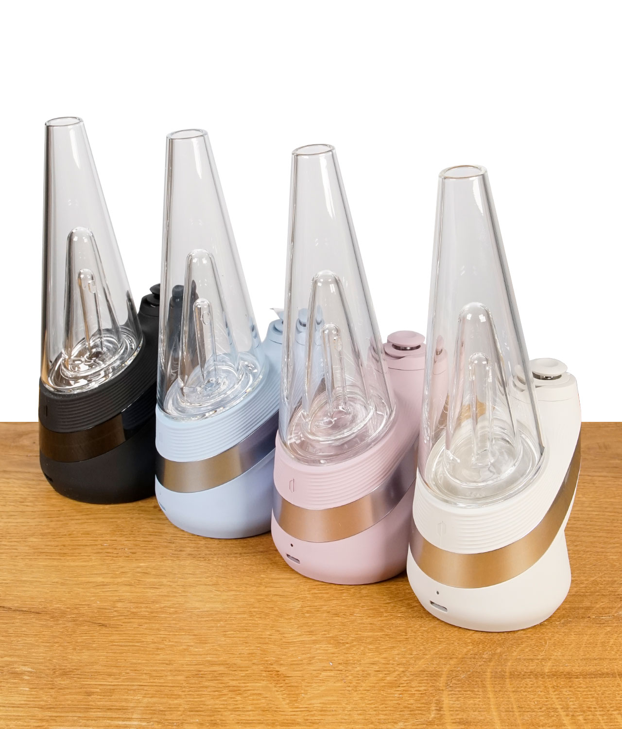puffco-new-peak-2024-gruppenbild-jpg Vier Puffco New Peak Vaporizers in den Farben Cloud, Onyx, Bliss und Sky nebeneinander auf Holz.