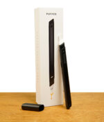 Das schwarze Puffco Hot Knife Onyx mit frei liegender Kappe an der Verpackung angelehnt.