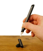 Hand hält das Puffco Hot Knife Onyx beim Gebrauch. Die Kappe liegt auf einem Stein darunter.
