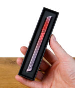 Eine Hand hält das Puffco Hot Knife Rink in der schwarzen Verpackung des Dabbing Tools