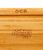 Nahaufnahme der Gravur „100% Natural Experience OCB“ auf der Holzoberfläche.