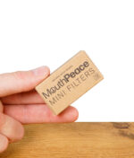 Hand hält eine geschlossene Packung MouthPeace Mini Filter mit Aufschrift „activated carbon filtration“.