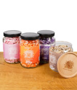 Medusafilters Gläser der Rosé, Sunset, Violet und Organic Edition mit abgenommenem Holzdeckel der Organic Edition im Vordergrund.