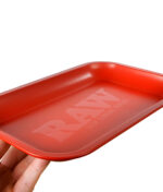 RAW Rolling Tray in matt rot aus seitlicher Perspektive, leicht angewinkelt in einer Hand gehalten.