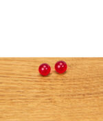 Zwei rote Rubin Pearls aus Glas nebeneinander auf einer Holzfläche