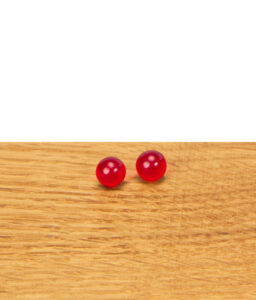 Zwei rote Rubin Pearls aus Glas nebeneinander auf einer Holzfläche