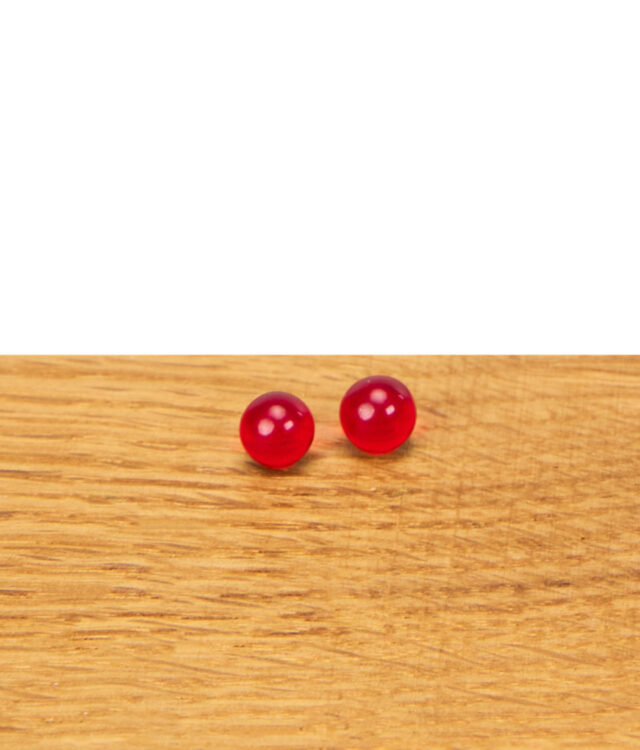 Zwei rote Rubin Pearls aus Glas nebeneinander auf einer Holzfläche