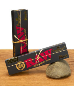 Zwei Packungen RAW Black Connoisseur Papers mit goldener Kordel auf Holztisch arrangiert.