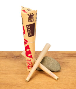 Drei RAW Classic King Size Cones mit Verpackung auf Holzuntergrund vor weißem Hintergrund