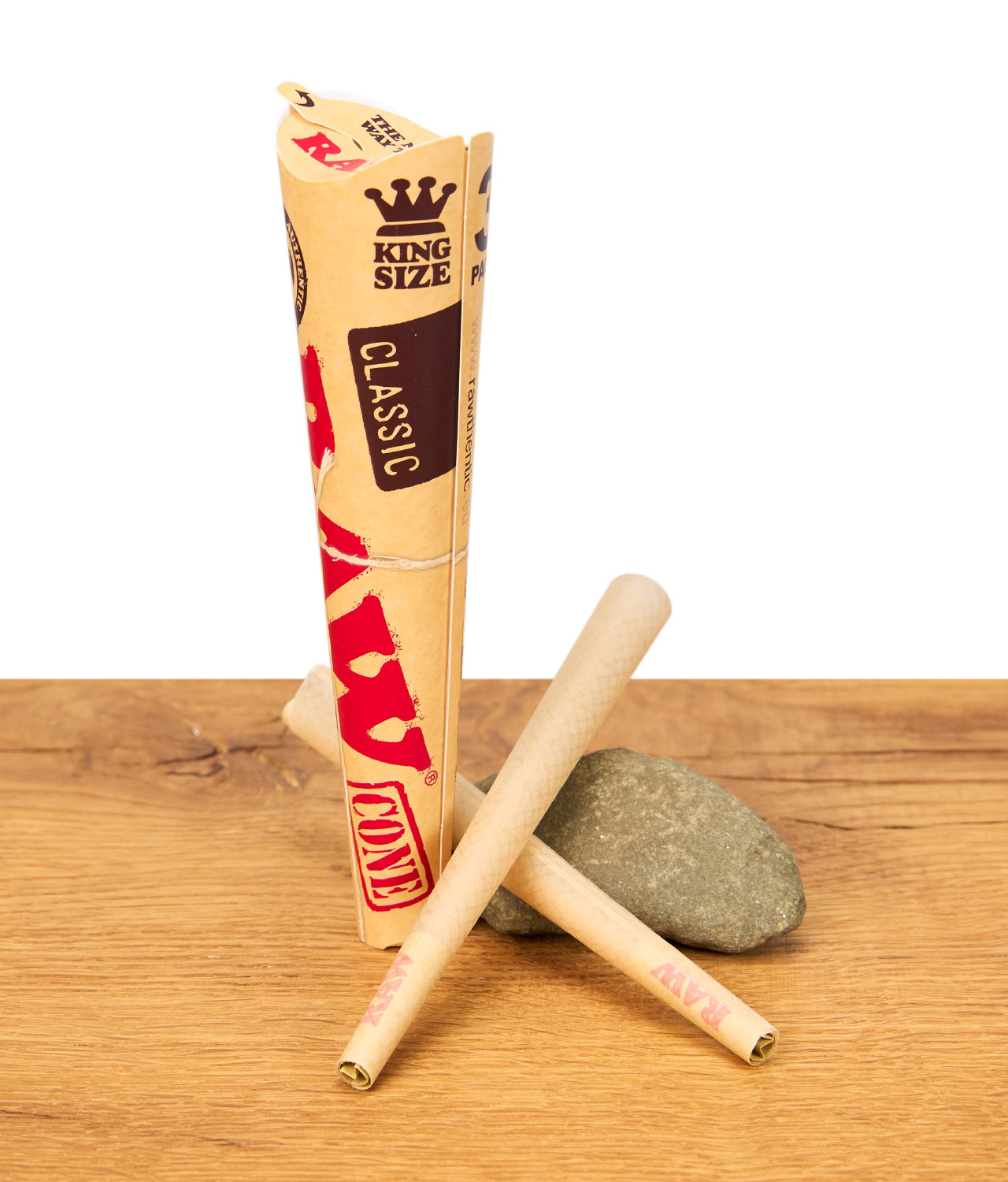 rawclassic-king-size-cones-3er-pack-jpg Drei RAW Classic King Size Cones mit Verpackung auf Holzuntergrund vor weißem Hintergrund