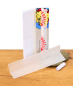 Einzelnes The Bulldog Silver King Size Paper vor der offenen Verpackung mit sichtbaren Filtertips und einem gerollten Tip, arrangiert auf einem Stein