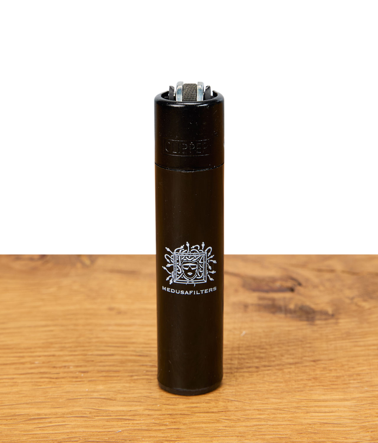 medusafilters-clipper-feuerzeug-schwarz Schwarzes Clipper Feuerzeug mit Medusafilters-Logo auf einer Holzoberfläche.