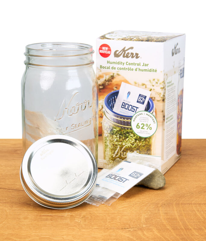 Aufbewahrungsglas mit Integra Boost Feuchtigkeitsregulierer und Verpackung auf einem Holzbrett