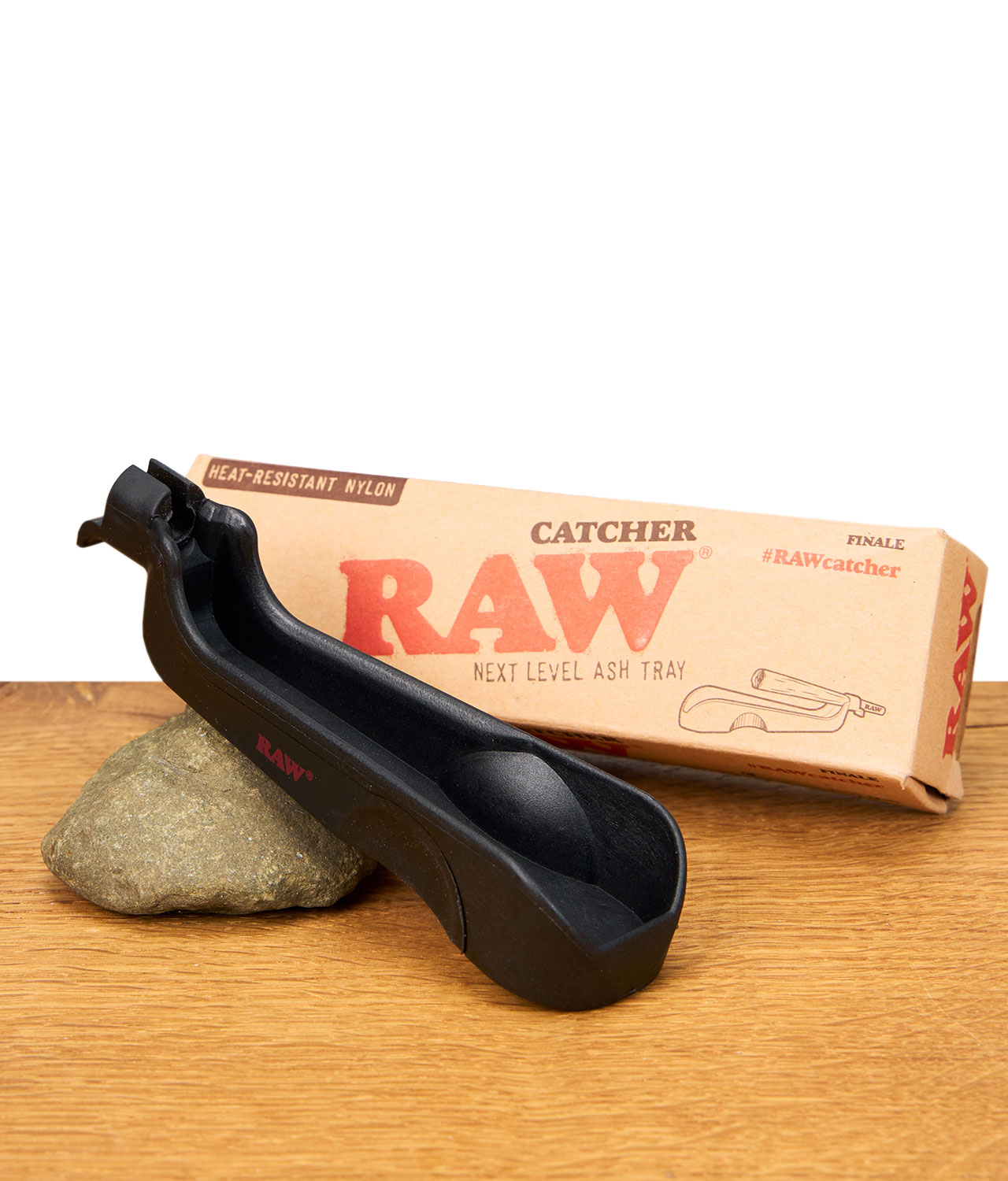 RAWcatcher-1-jpg RAW Catcher Aschenbecher aus schwarzem Nylon vor seiner Verpackung, auf einem Stein und einem Holzuntergrund liegend.