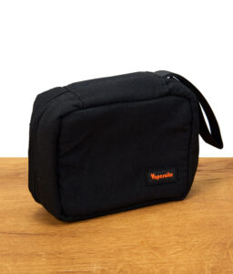Schwarze Vapesuite Vaporizer-Tasche mit Reißverschluss und orangefarbenem Vapesuite-Logo, steht auf einem Holztisch.