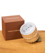 Tobacco Grinder auf einem Stein mit Verpackung im Hintergrund auf einem Holzbrett