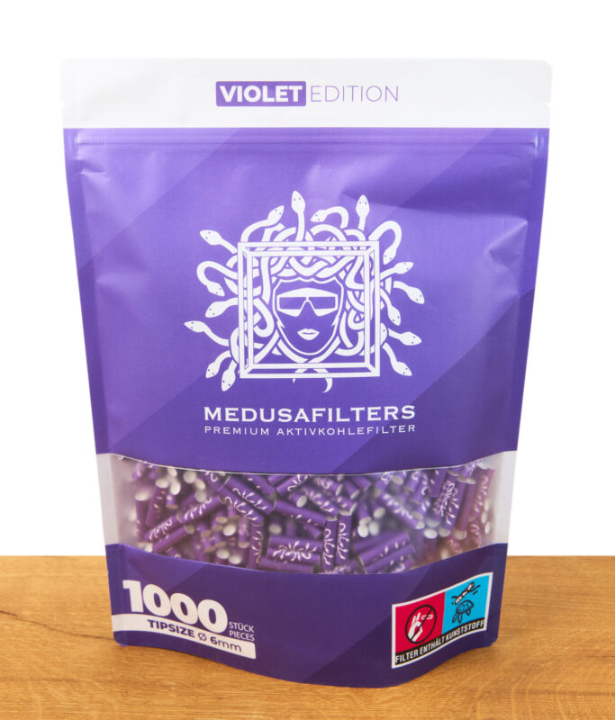 Lila Verpackung „Medusafilters Violet Edition“ mit Sichtfenster, gefüllt mit 1000 Aktivkohlefiltern in 6 mm Größe, Medusa-Logo und Produktdetails auf der Vorderseite.
