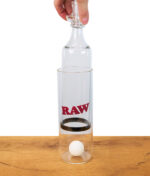 Person zieht den Einsatz des RAW Gravity Cone aus dem Glaszylinder, Produktvorführung auf Holztisch.