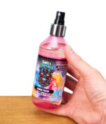 Hand hält eine pinke Flasche Smell Crusher Fabric Fresh Textilparfüm und Geruchsentferner, Produktfoto auf weißem Hintergrund.