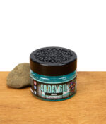 Smell Crusher 40 Day Gel Breeze Lufterfrischer im Glasbehälter mit schwarzem Deckel und Stein, Produktfoto auf Holztisch.