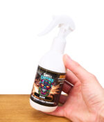Hand hält Smell Crusher Air Freshener & Odor Eliminator Spray Black in weißer Flasche mit Feuerdesign, Studioaufnahme.