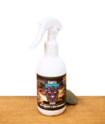 Smell Crusher Air Freshener & Odor Eliminator Spray Black, weiße Flasche mit Feuerdesign-Etikett, stehend auf Holztisch mit Stein.