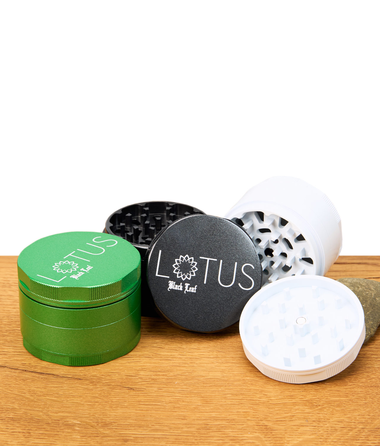 black-leaf-lotus-grinder-63mm-1-jpg Black Leaf Lotus Grinder 63mm in Grün, Schwarz und Weiß, teilweise geöffnet und gestapelt auf Holztisch