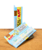 RAW Rolling Papers x Lyrical Lemonade in King Size, organische Verpackung und gebrandetes Hanfpapier auf Holzoberfläche.