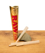 RAW Ethereal Cones 1 1/4 Size 6er Pack in goldener Verpackung, zwei vorgedrehte Cones auf Holztisch